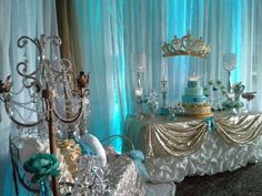 a table topped with a cake covered in frosting and surrounded by crystal vases