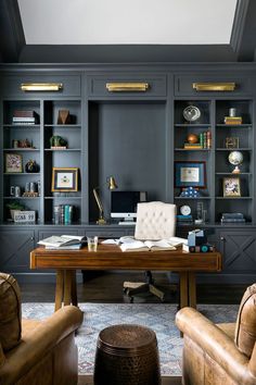 a home office with built - in bookcases and leather chairs, along with a desk