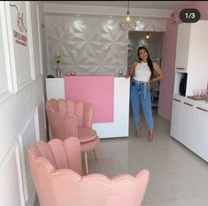 a woman standing in a kitchen next to pink chairs