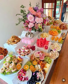 a table filled with lots of different types of food and flowers in vases on top of it