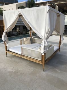 an outdoor bed with white sheets and pillows