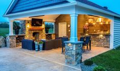 an outdoor living area with stone fireplace and grill in the back yard at night time