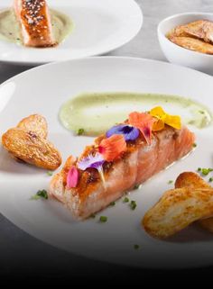 a white plate topped with fish next to potato wedges