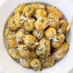 a white bowl filled with pasta covered in parmesan cheese and sprinkled with parsley