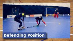 two young men are playing hockey on an indoor court with the words defending position in front of them