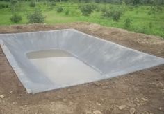 an empty pool in the middle of a field with trees in the background and dirt on the ground