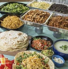 many different types of food are displayed on a table with plates and bowls full of salads