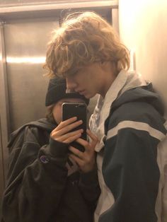 a young man is looking at his cell phone while standing in an elevator with the door open