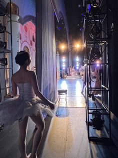 a woman in a white dress is sitting on a ledge and looking at the stage