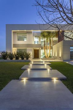 a modern house is lit up at night with lights on the steps leading to it