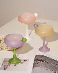 an open book sitting on top of a table next to two vases and a plate