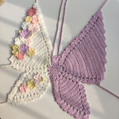 two crocheted butterflies are sitting on a white plate with pink and yellow flowers