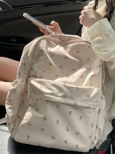 a woman sitting in the back seat of a car using her cell phone and purse