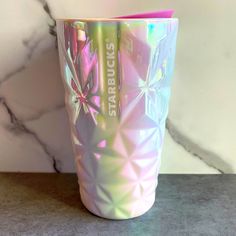 a colorful tumbler cup sitting on top of a counter next to a marble wall