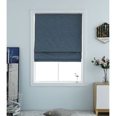 a living room with blue walls and white carpeted flooring, two windows covered in gray roman shades