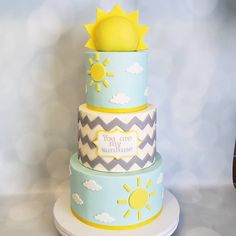 a three tiered cake decorated with sun and clouds