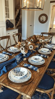 a dining room table set with blue and white plates, napkins and place settings