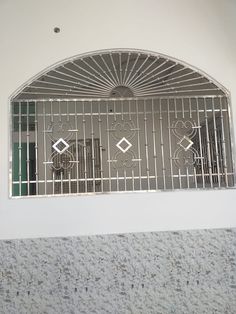 an arched window with metal bars in the middle and decorative designs on the outside wall