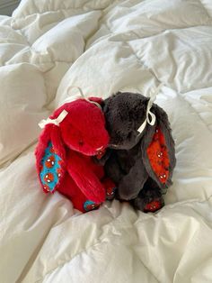 two stuffed animals sitting on top of a bed