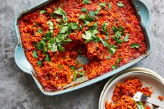 a casserole dish filled with red rice and garnished with parsley