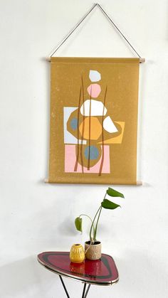 a painting hangs on the wall next to a small table with a potted plant