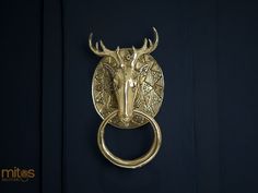 a golden deer head mounted to the side of a black wall with a ring on it