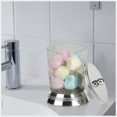 a glass filled with bath balls sitting on top of a counter next to a soap dispenser