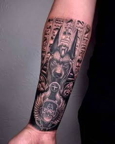 a man's arm with an egyptian tattoo design on the left side of his arm