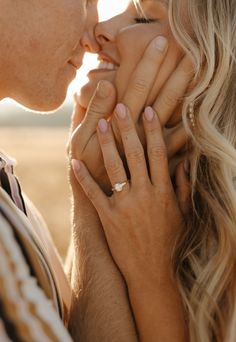 a man and woman holding each other close to their face with the sun shining on them