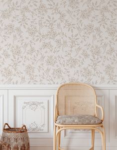 a chair sitting next to a basket in front of a wall with flowers on it