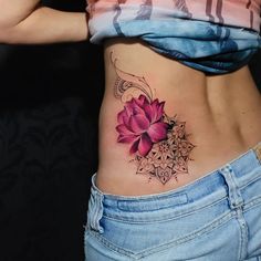 a woman's stomach with a pink flower tattoo on her lower back and side