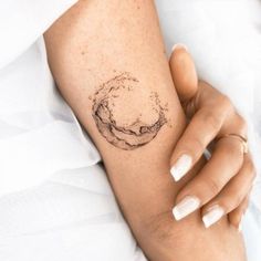 a woman's arm with a circle tattoo on it