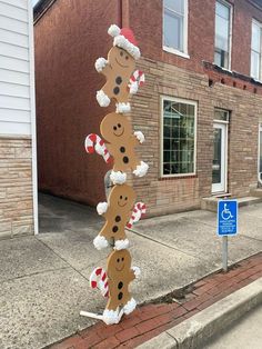 a street sign with gingerbreads and candy canes attached to it on the sidewalk in front of a brick building