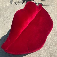 a red heart shaped chair sitting on top of a cement floor next to a bike