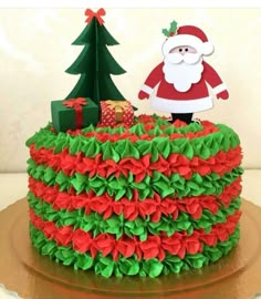 a christmas cake decorated with green and red ruffles, santa clause standing on top