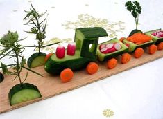 a carved vegetable train with carrots, cucumbers and radishes on it