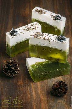 three soap bars sitting on top of a wooden table next to pine cones and an evergreen cone