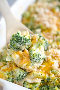 broccoli and cheese casserole in a white dish with a wooden spoon