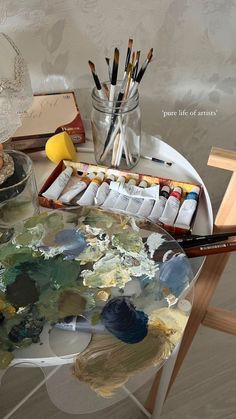 a table with paint, brushes and other art supplies