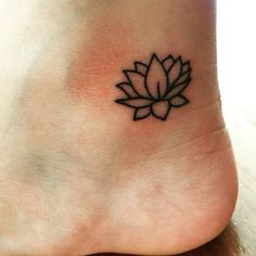 a small lotus flower tattoo on the side of someone's foot with black ink