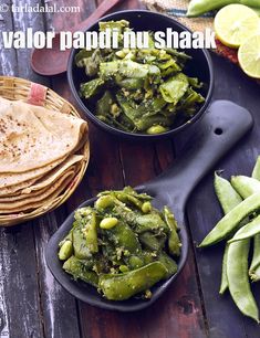 two black bowls filled with green vegetables next to some pita bread and lime wedges