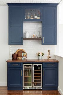 a kitchen with blue cabinets and wooden counter tops in the center is an open wine cooler