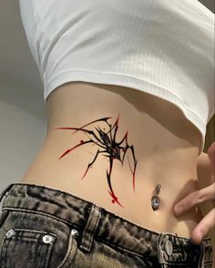 a woman's stomach with a spider tattoo on the side and red paint splatters