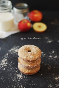 apple cider donuts stacked on top of each other with powdered sugar and apples in the background