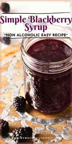 a jar filled with blackberry syrup on top of a wooden table next to blackberries