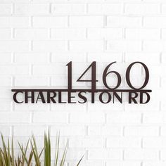 a metal sign that says,'480 charleston rd'in black on a white brick wall