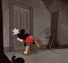 a mickey mouse standing in front of a door