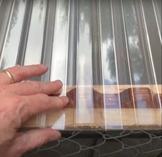 a person holding onto a piece of metal on top of a fence