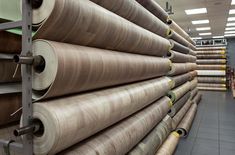 many rolls of fabric are lined up in a warehouse