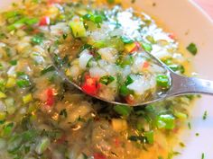 a white plate topped with rice and vegetables next to a spoon on top of it